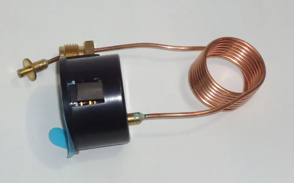Manometer von Daikin, angeschlossen an eine Kupferleitung, zeigt Druckmessung bis 4 bar an. Kompakte Bauform mit einer spiralförmigen Leitung.